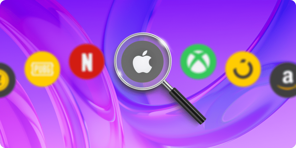 Magnifying glass focusing on Apple gift card logo surrounded by other digital gift card icons including Netflix, Xbox, PUBG, and Smile on a purple background
