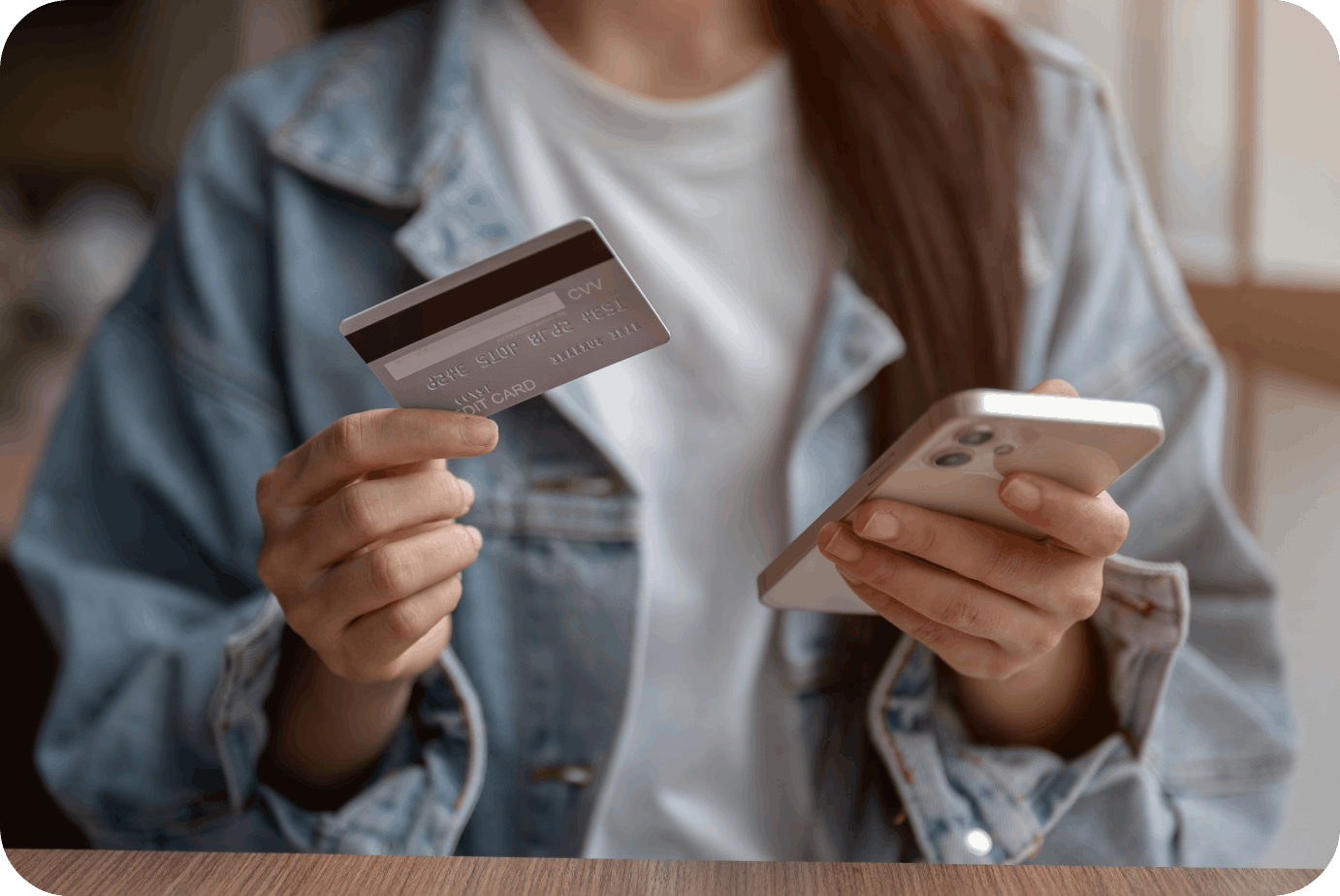 Woman holding credit card and smartphone while completing online payment, representing step-by-step digital gift card redemption process.